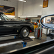 A black Porsche 356 convertible is on an alignment rack.